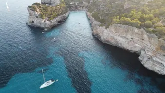 Crique aux falaises claires avec le voilier au mouillage, vue du ciel